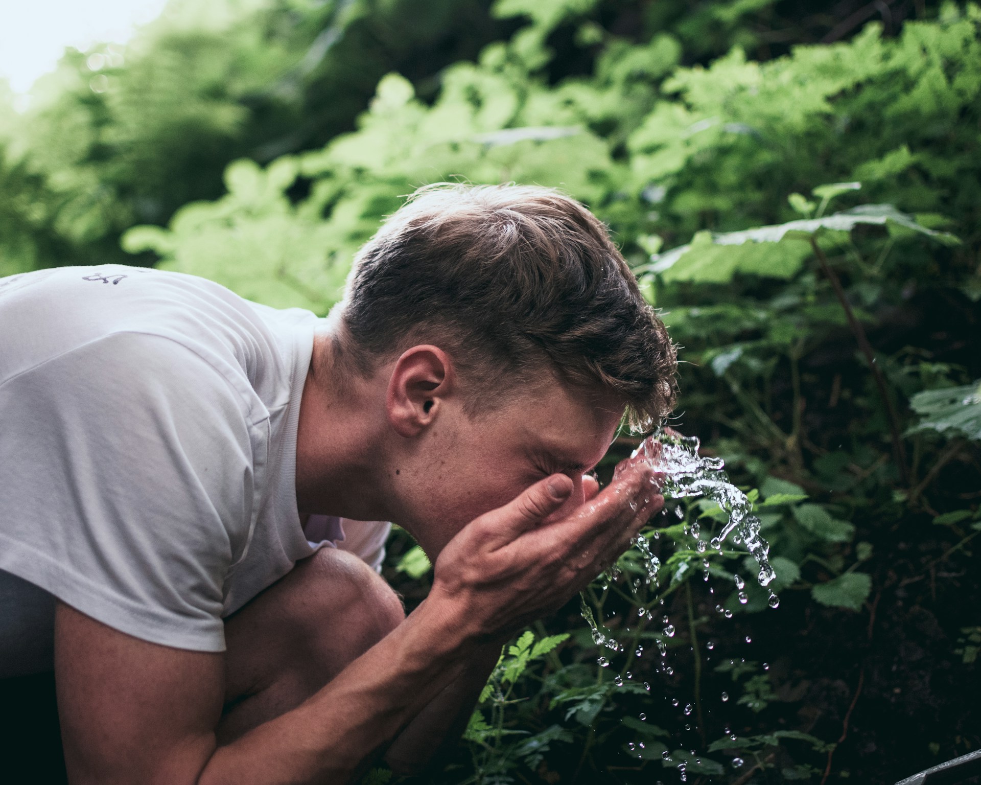 Man splashing water on his face outdoors, symbolizing renewal, mindfulness, and the healing power of nature in recovery